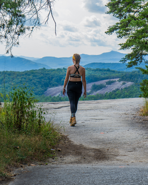 Woman walking along a path leading to stone faced mountains