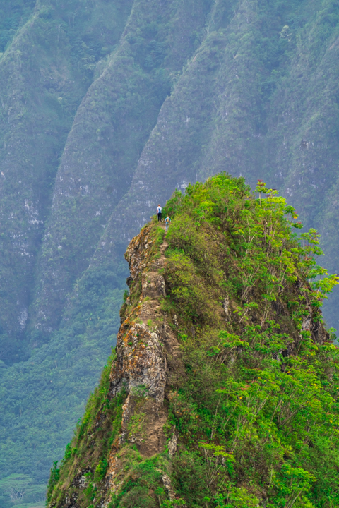 Two people hiking up the third Olomana peak