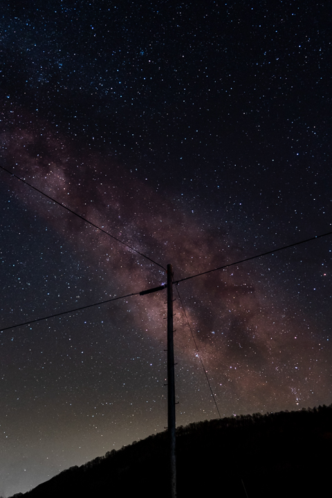 the milkyway behinf a silouette of a powerline pole