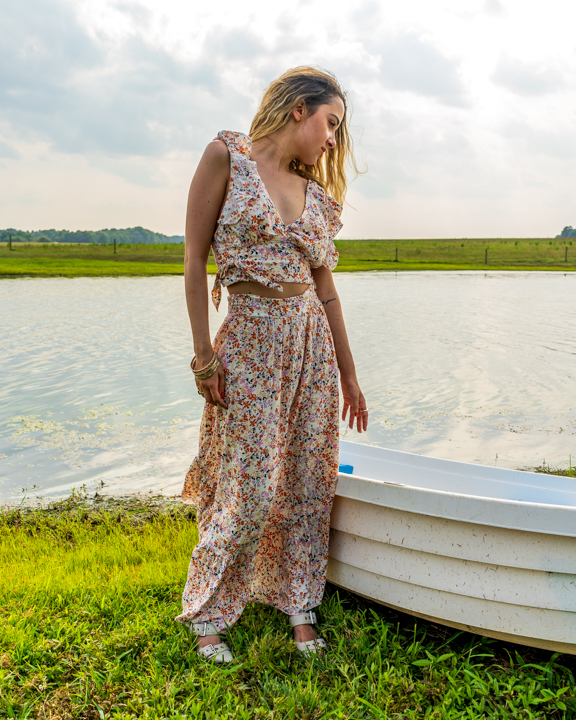 Woman in a folral dress lakeside reaching for a boat to her side